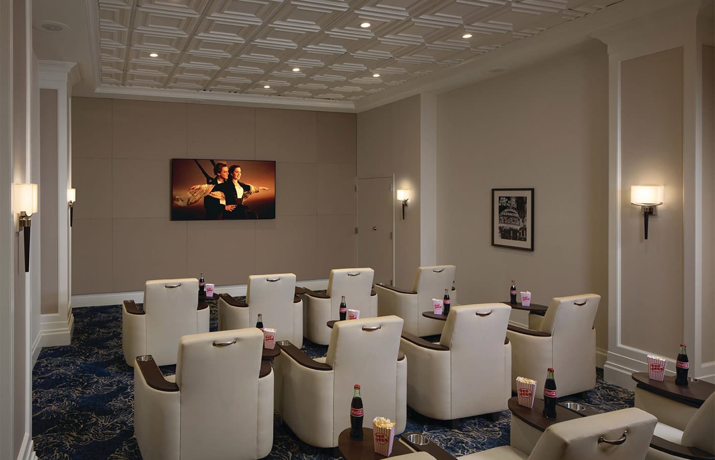 A look inside the theatre at the Watermark at Brooklyn Heights showcasing a film playing on a large tv screen with reclining lazyboy theatre style seating