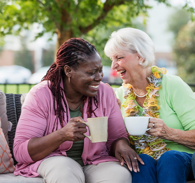 Two elderly woman laughing and enjoying a cup of coffee