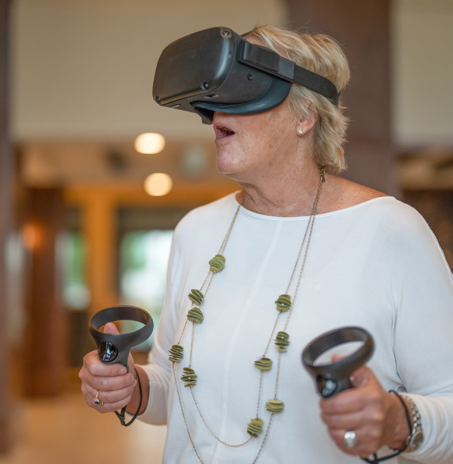 Elderly woman with virtual reality goggles and controls 