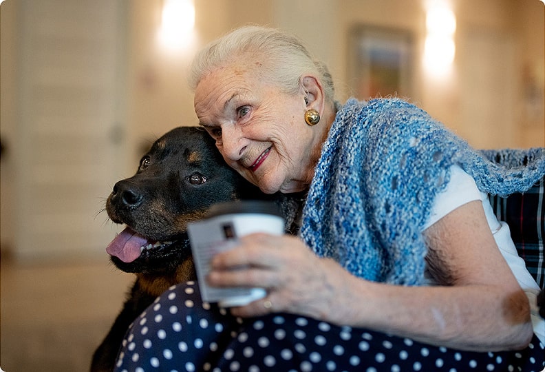 elderly woman hugging a black lab