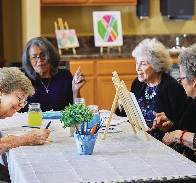 group of elderly woman sitting around a table painting