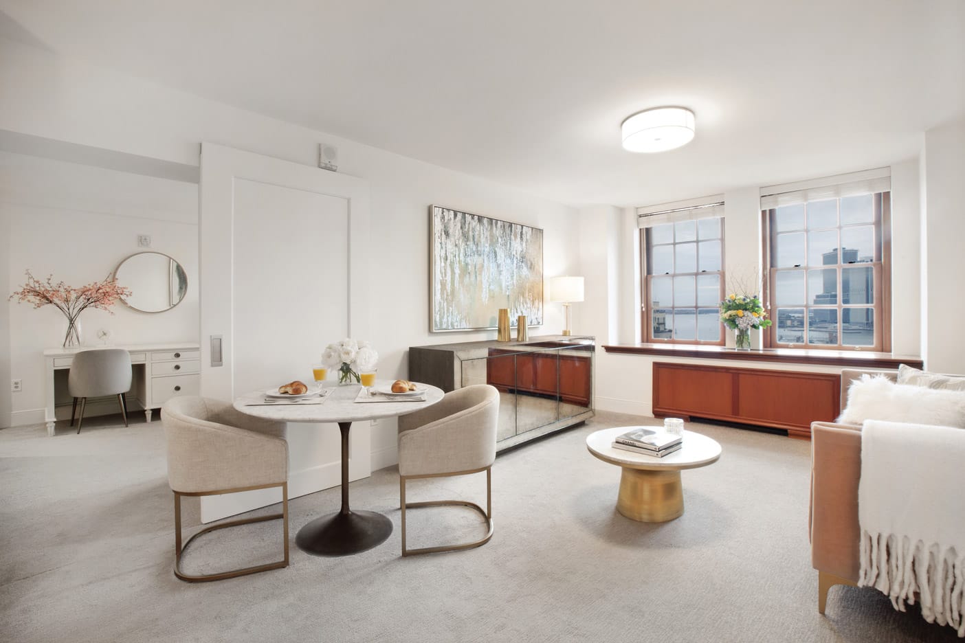 Brooklyn Heights Independent & Assisted Living Photo Gallery - living space layout featuring several pieces of tasteful artwork, several chairs with matching end tables, a view of New York through the mahogany framed windows, and a look into the bedroom