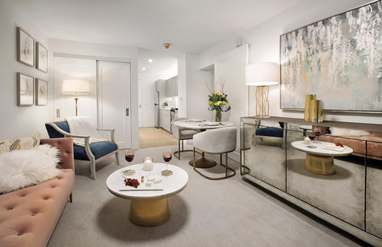 Brooklyn Heights Independent & Assisted Living Photo Gallery - living space layout featuring a couch, matching chair, round coffee table, small kitchen seating for two and a glimpse of the kitchen 