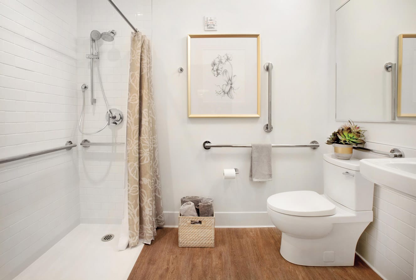 Brooklyn Heights Independent & Assisted Living Photo Gallery - a look at the bathroom featuring a walk-in shower with no lip, toilet, sink, and hand rails for added support and safety