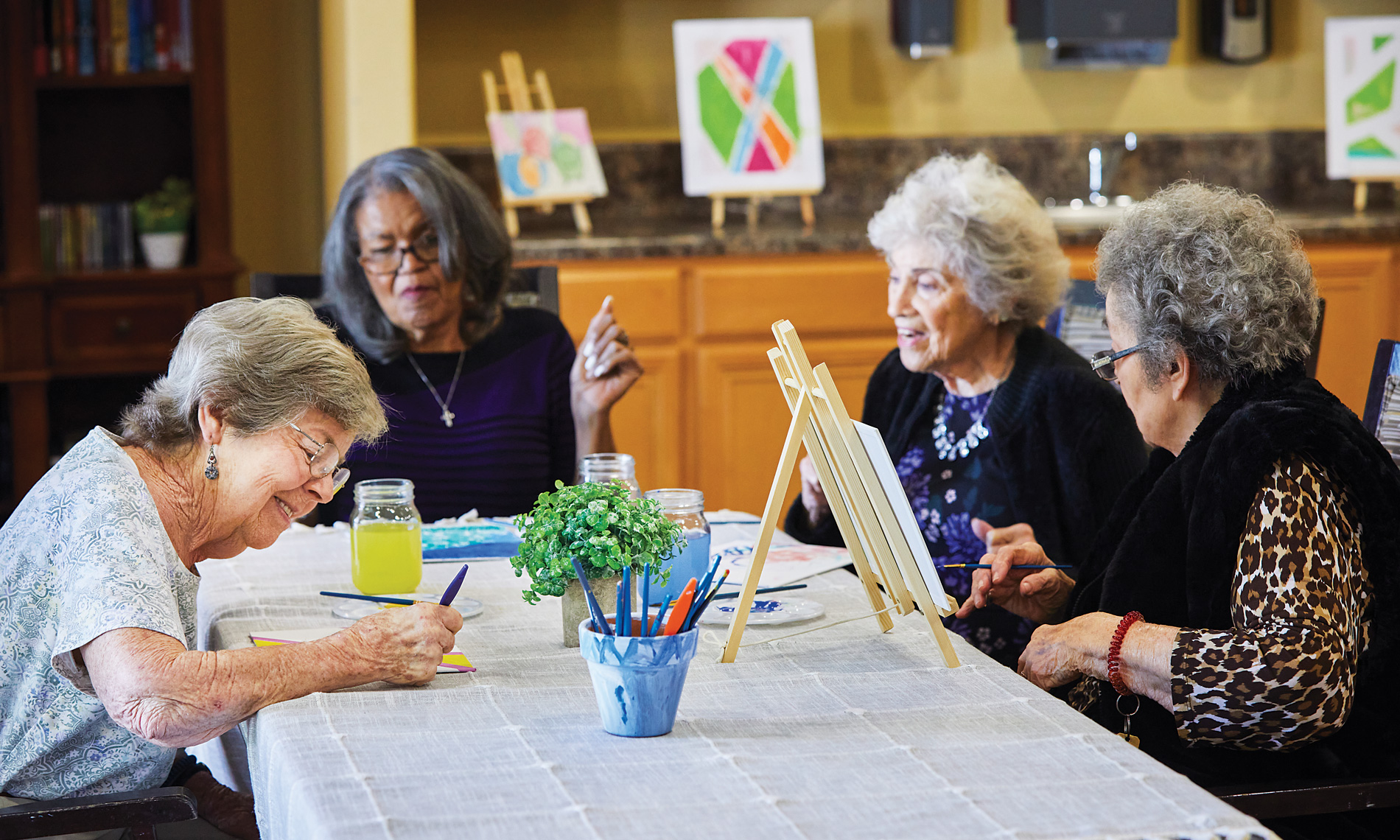 elderly women sitting around a table painting