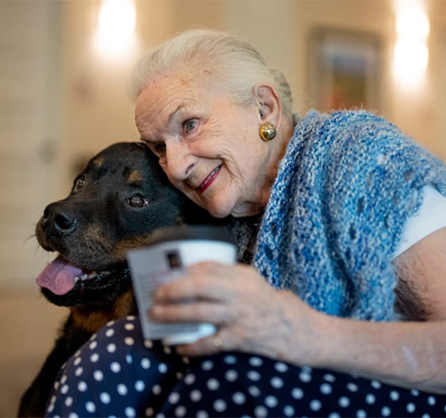 elderly woman hugging a black lab