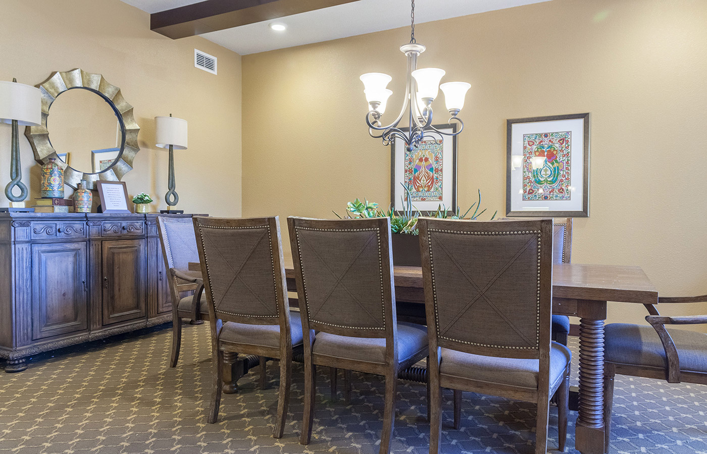 An eight place dining table with two picture frame on the adjacent wall