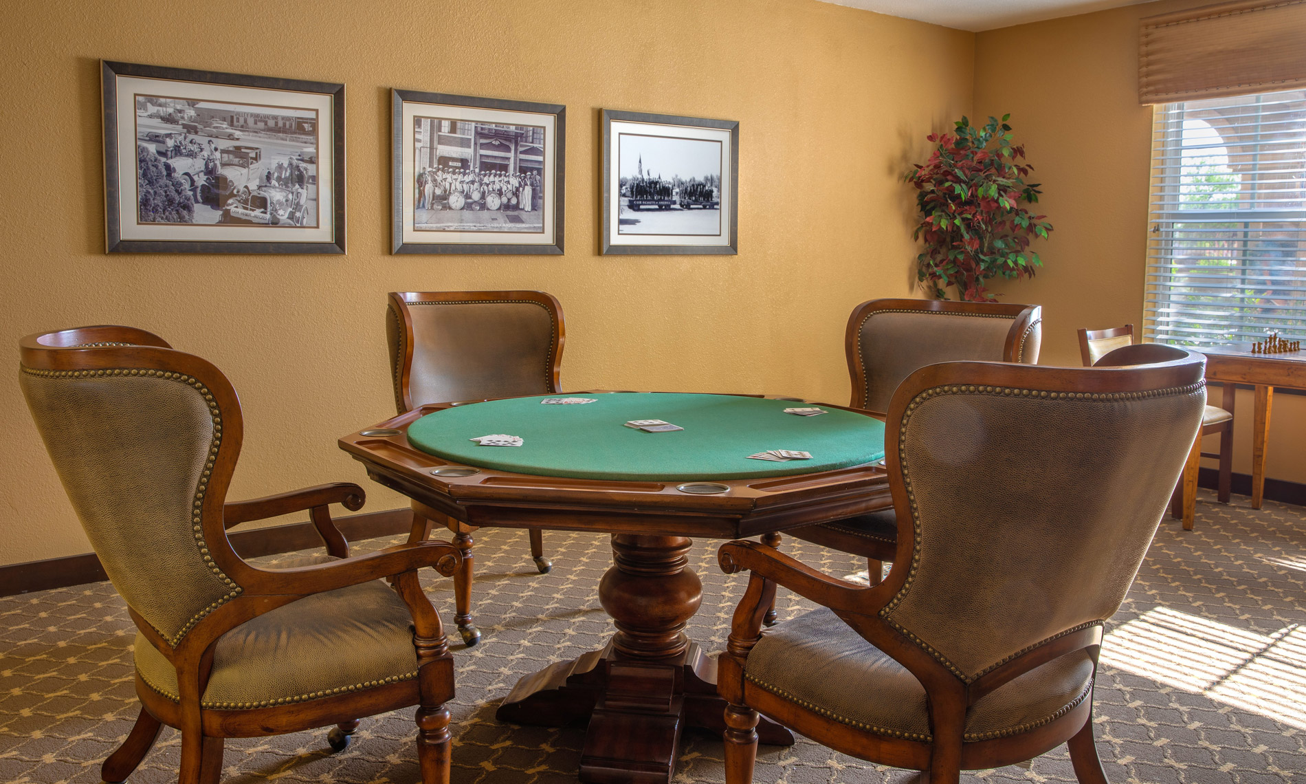 A poker table with multiple painting on the wall behind