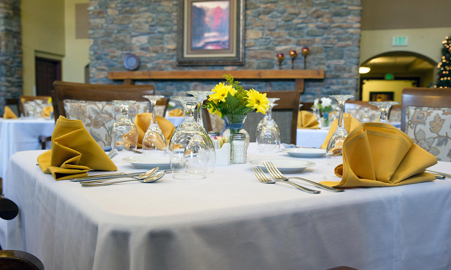 An elegant dinning table set with an array of silverware and yellow aprons