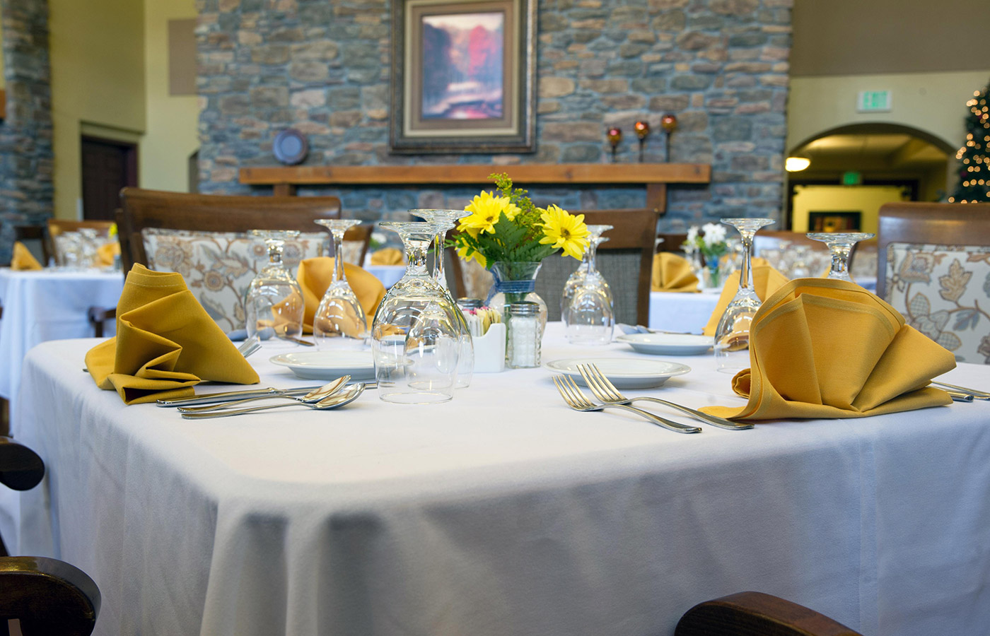 An elegant dinning table set with an array of silverware and yellow aprons