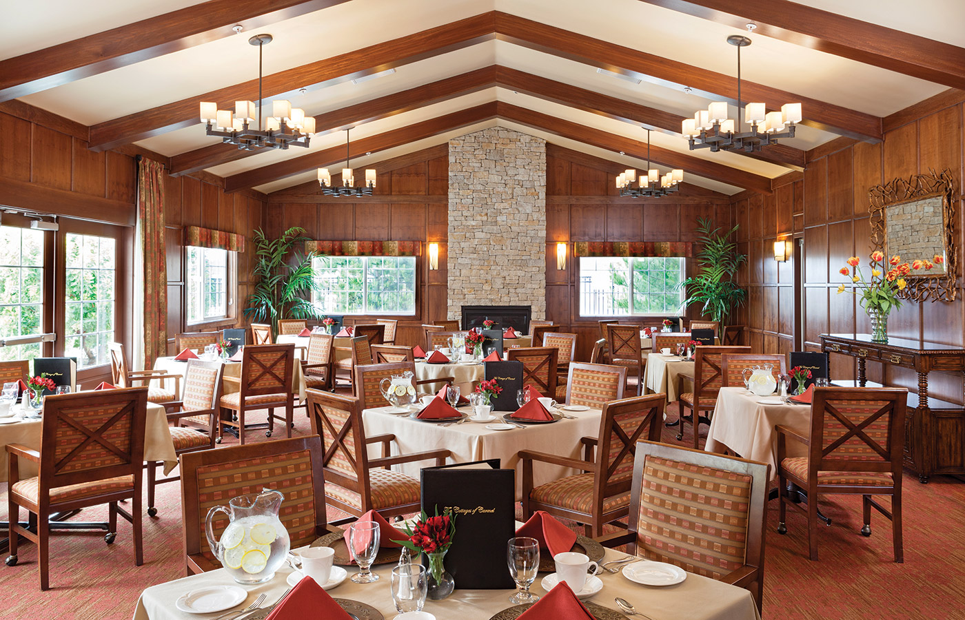 A large dining room with all table elegantly setup and large open window across the room 