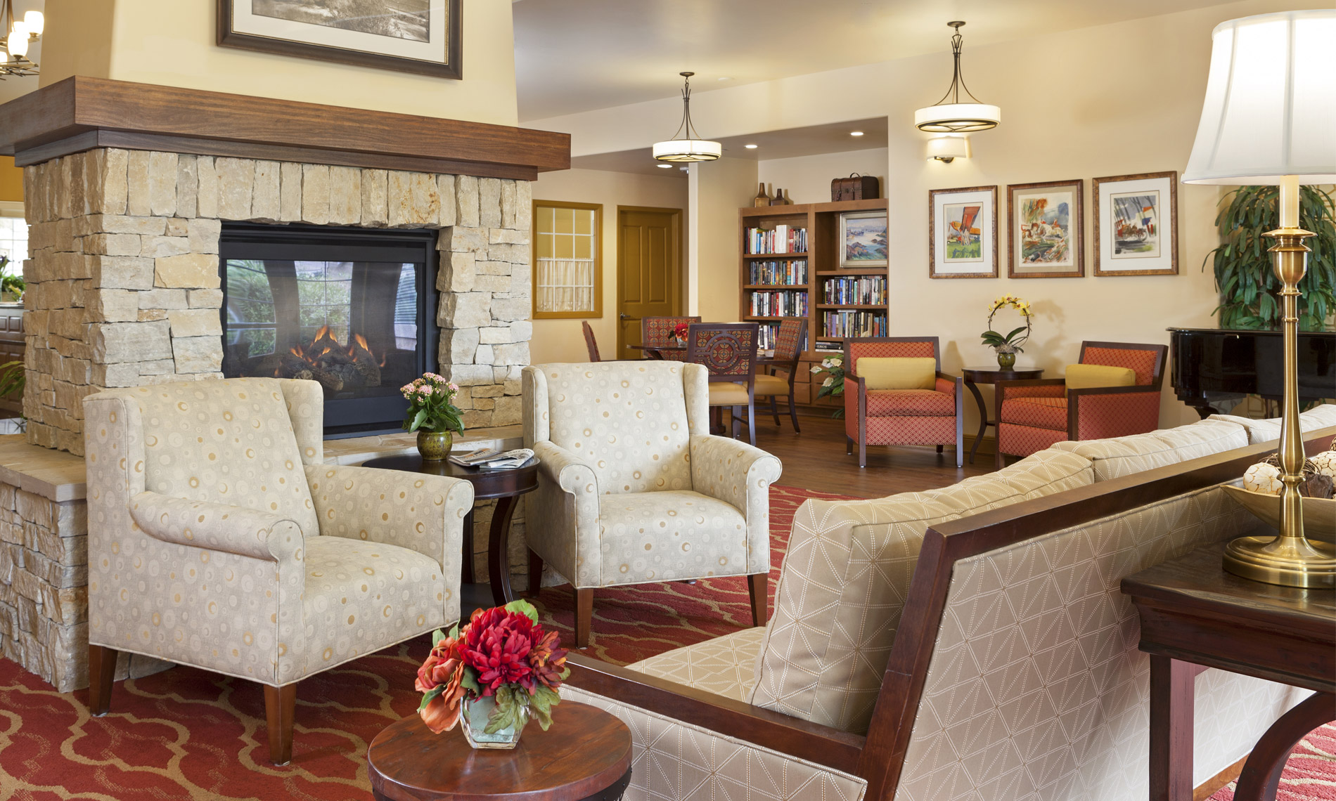 Hall with armchair, fireplace and a grand piano in the back by the bright windows