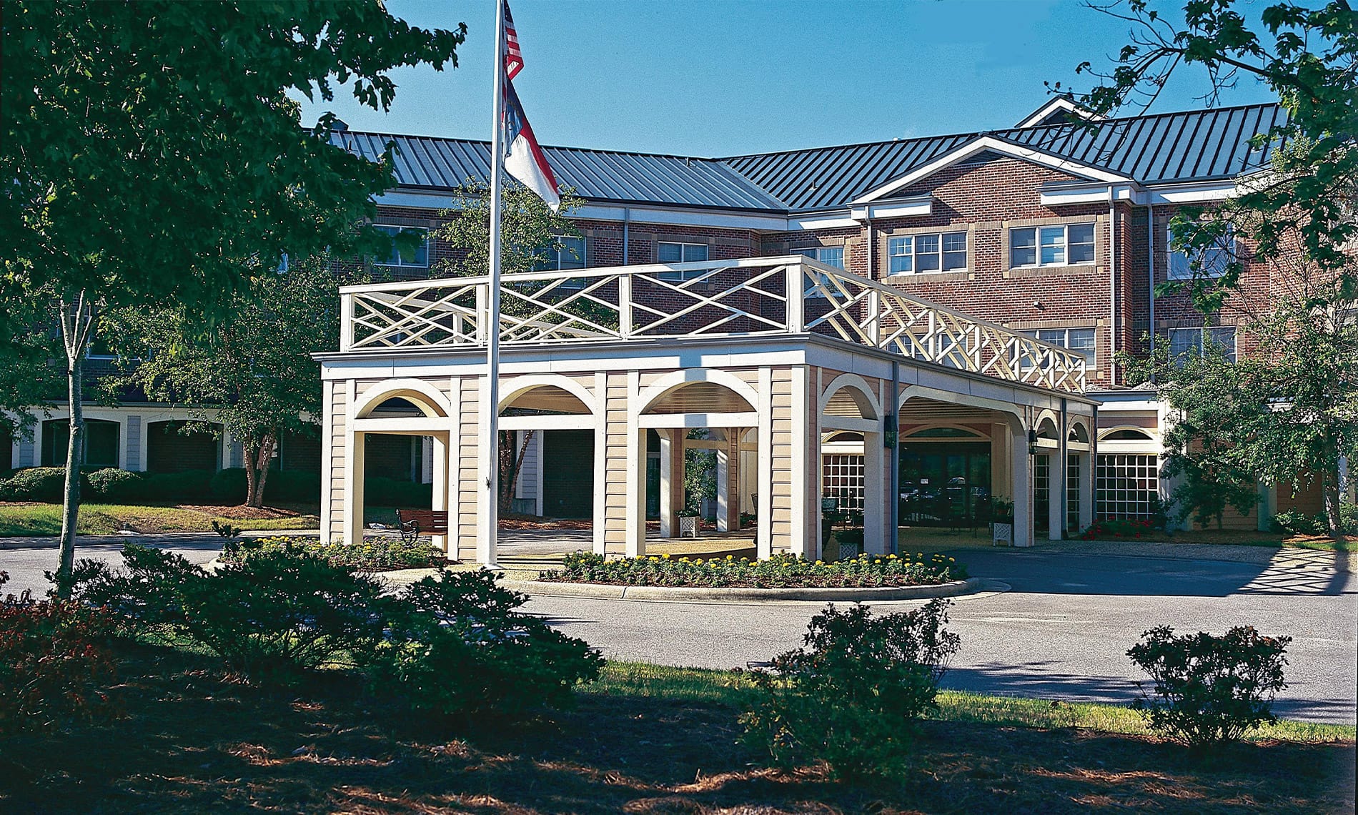 An exterior shot of the The Fountains at the Albemarle featuring an American flag and foliage in the foreground. 