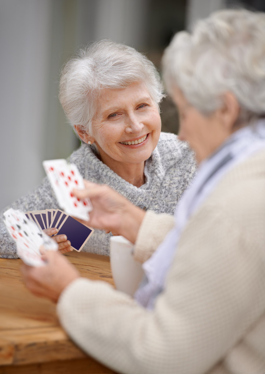 A pair of woman laughing over a game of cards