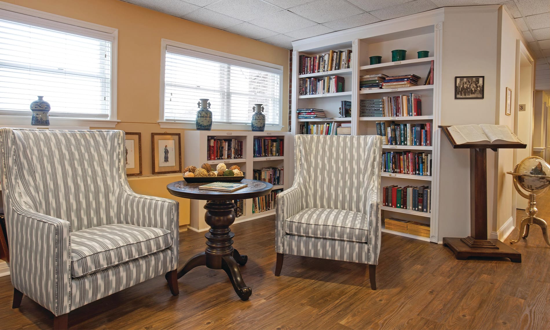 A chair and table in front of a built in book shelf within the on-site library at the Fountains at the Albemarle