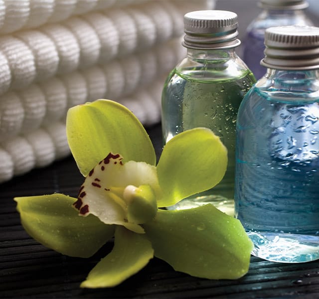 A vibrant green floral next to bottles of botanicals atop a wooden table