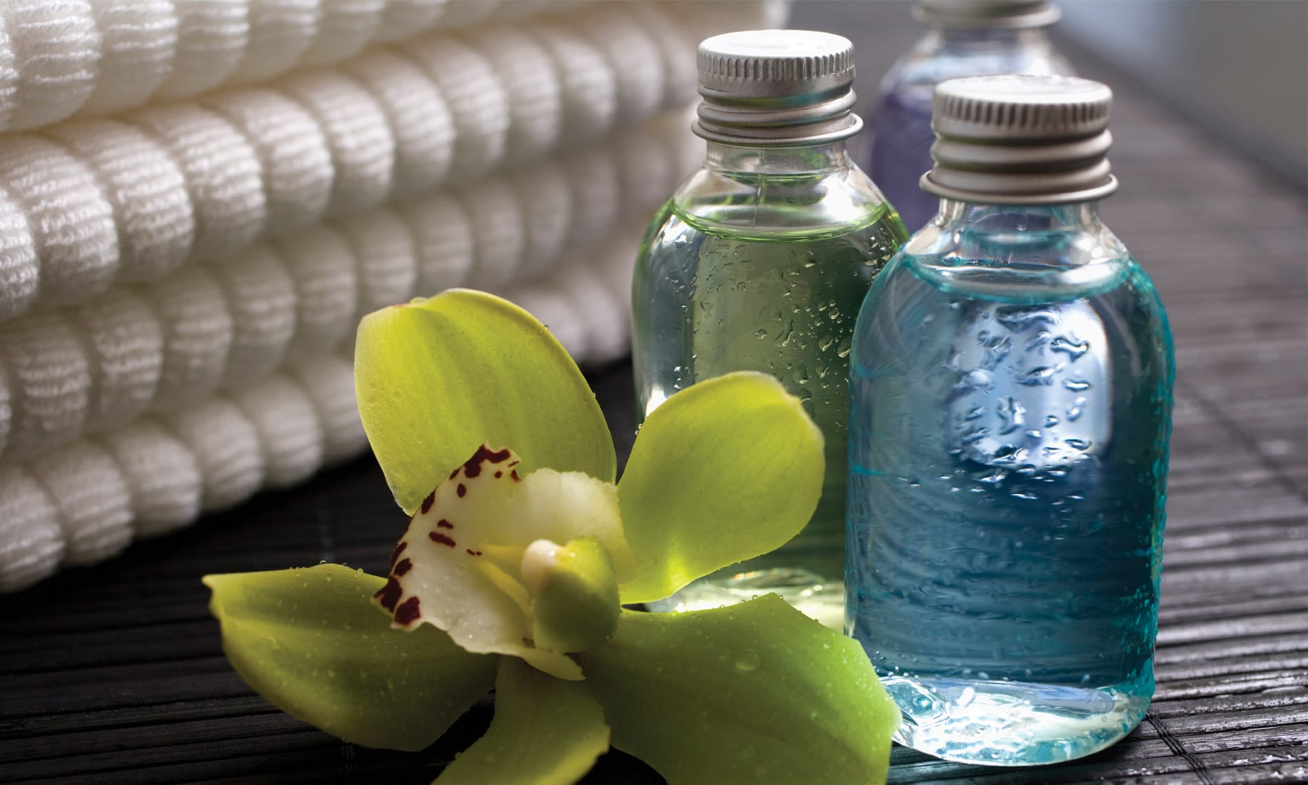 A vibrant green floral next to bottles of botanicals atop a wooden table