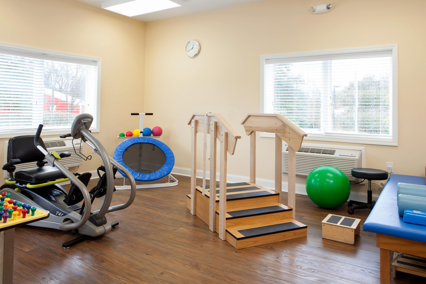 A fitness area at The Fountains at Albemarle featuring a stationary bike, trampoline, up/down staircase and a physio table