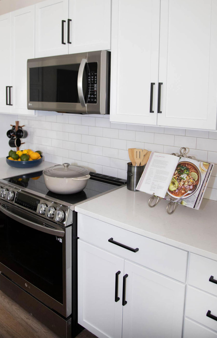 A modern kitchen showcasing a stainless steel electric stove and white cabinetry in a model residence at The Hacienda at the River