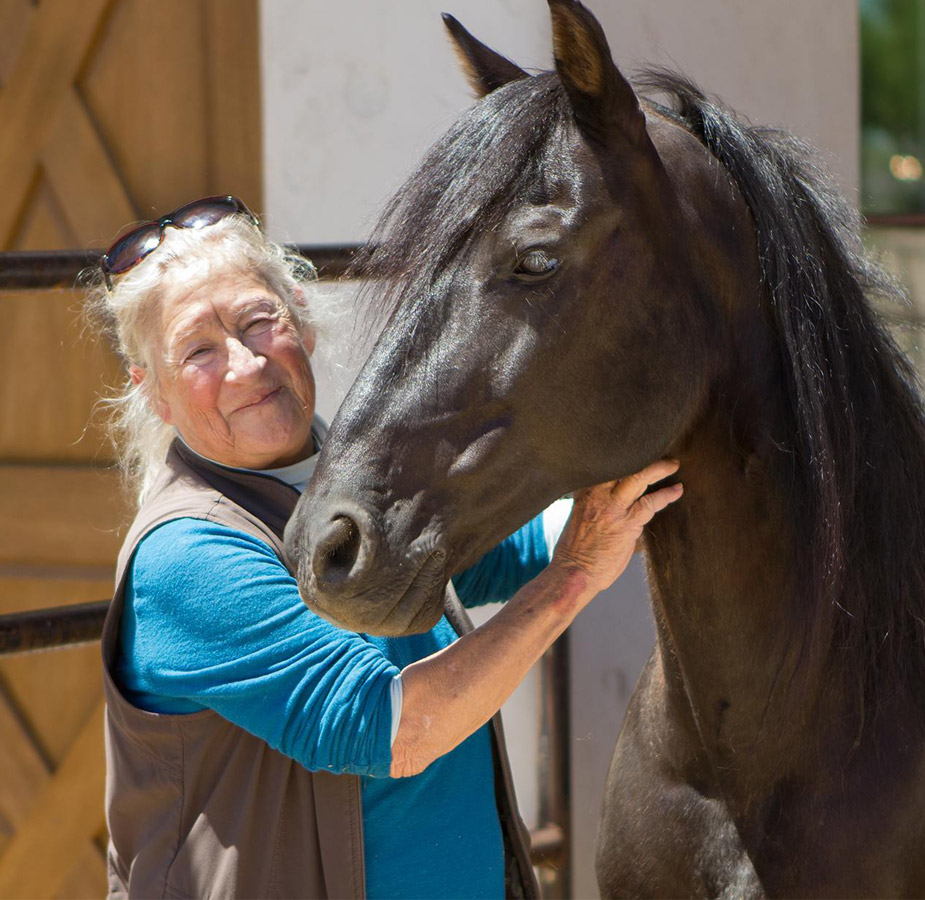 A female employee with a black horse at the stables on-site at The Hacienda at the River