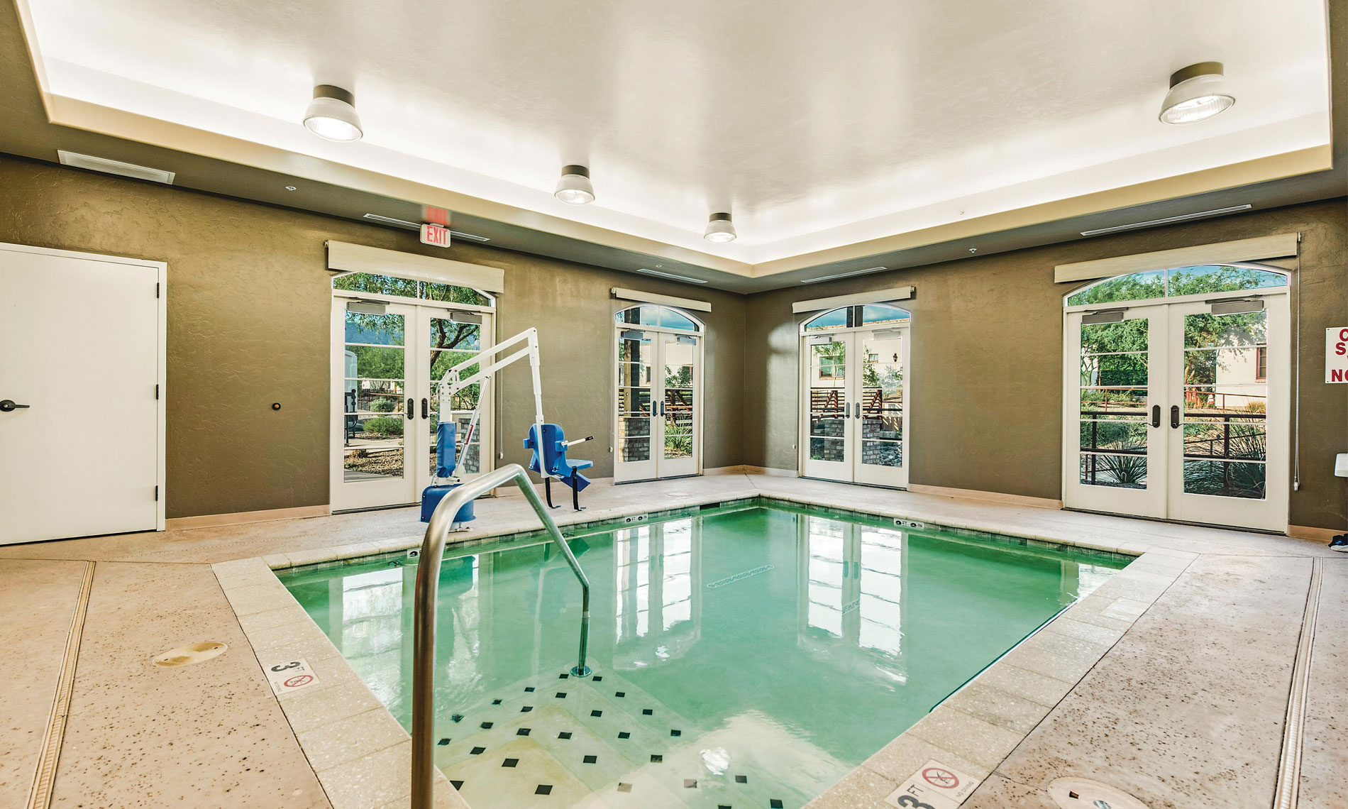 An indoor pool with chair that can be raised and lowered into the pool for individuals with mobility issues at The Hacienda at the River