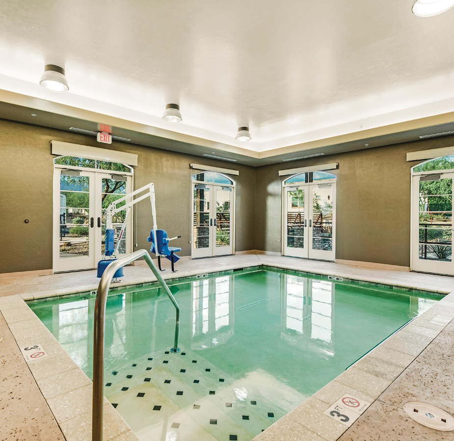 An indoor pool with chair that can be raised and lowered into the pool for individuals with mobility issues at The Hacienda at the River