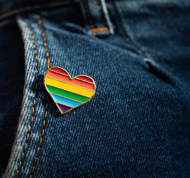 Rainbow color lgbt heart badge on jeans. Closeup photo