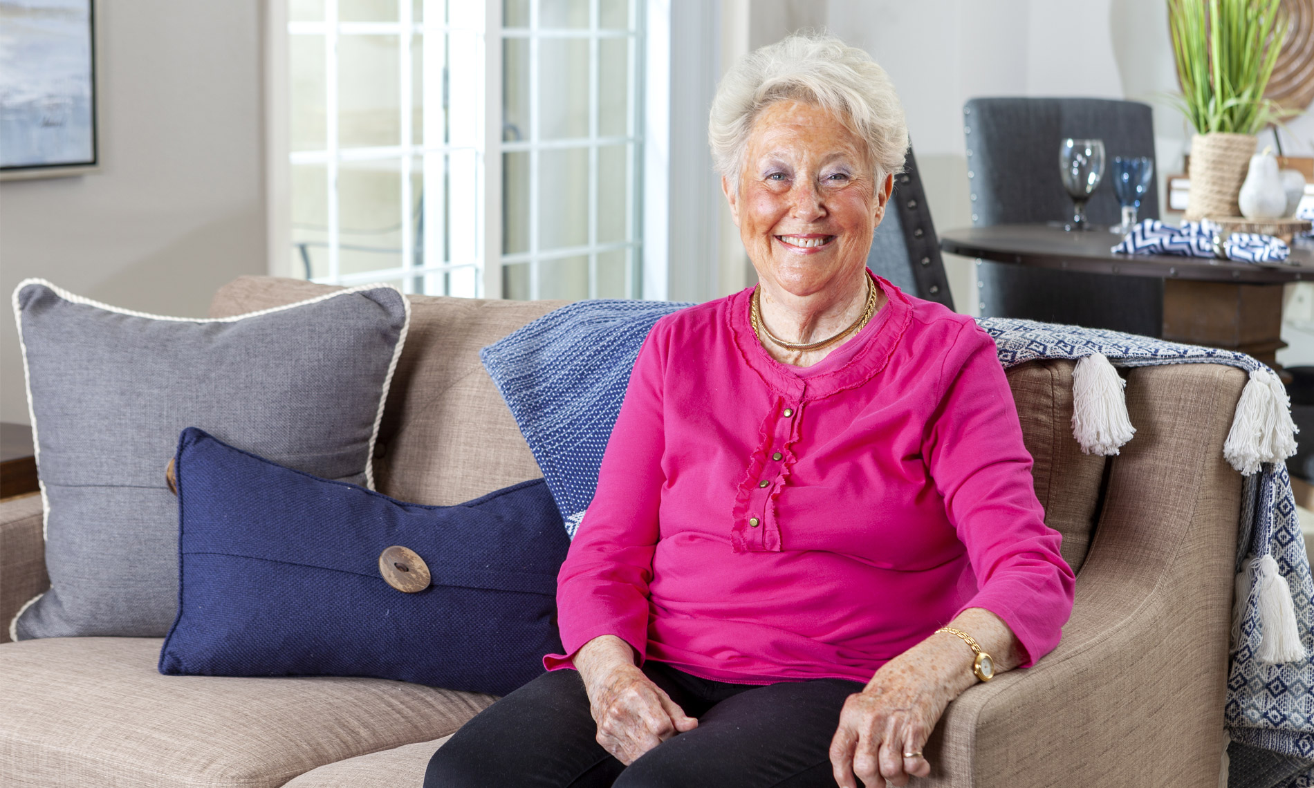 An elderly woman sitting on a cozy couch looking health and full of light