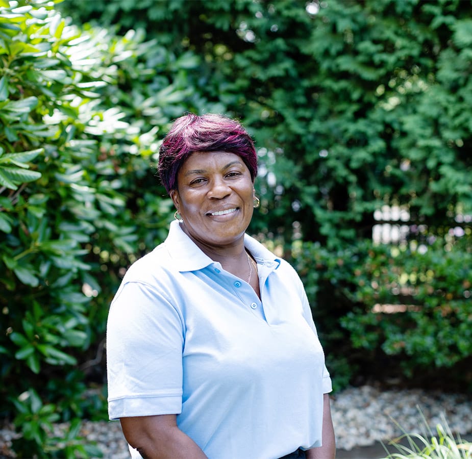 A Watermark employee standing outside with vibrant green shrubs in the background