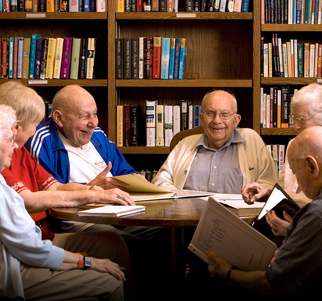 group of seniors and a staff member laughing while painting