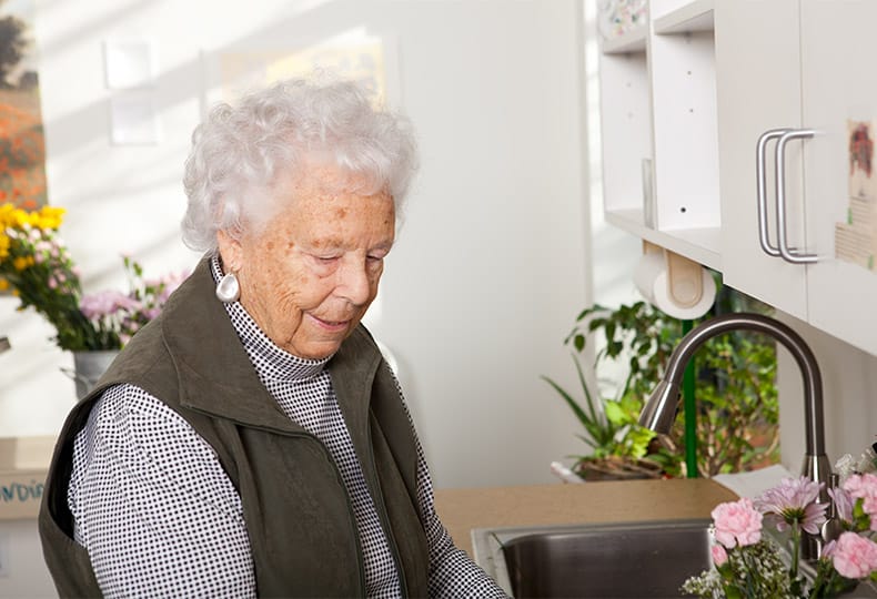 A female resident tending to various potted plants smiling to herself