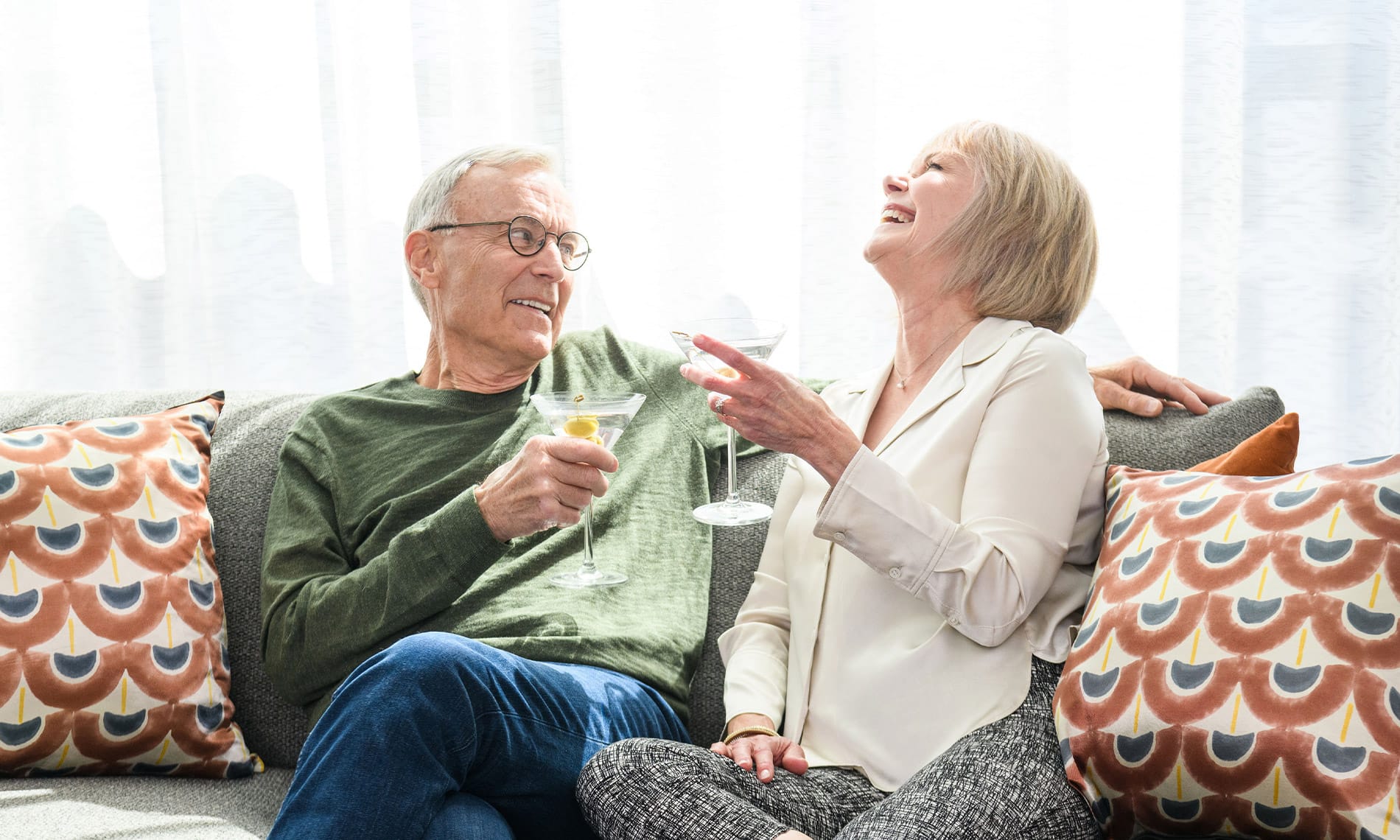 Residents laughing on a couch in their apartment at one of the many properties Watermark Retirement Communities operates across the United States