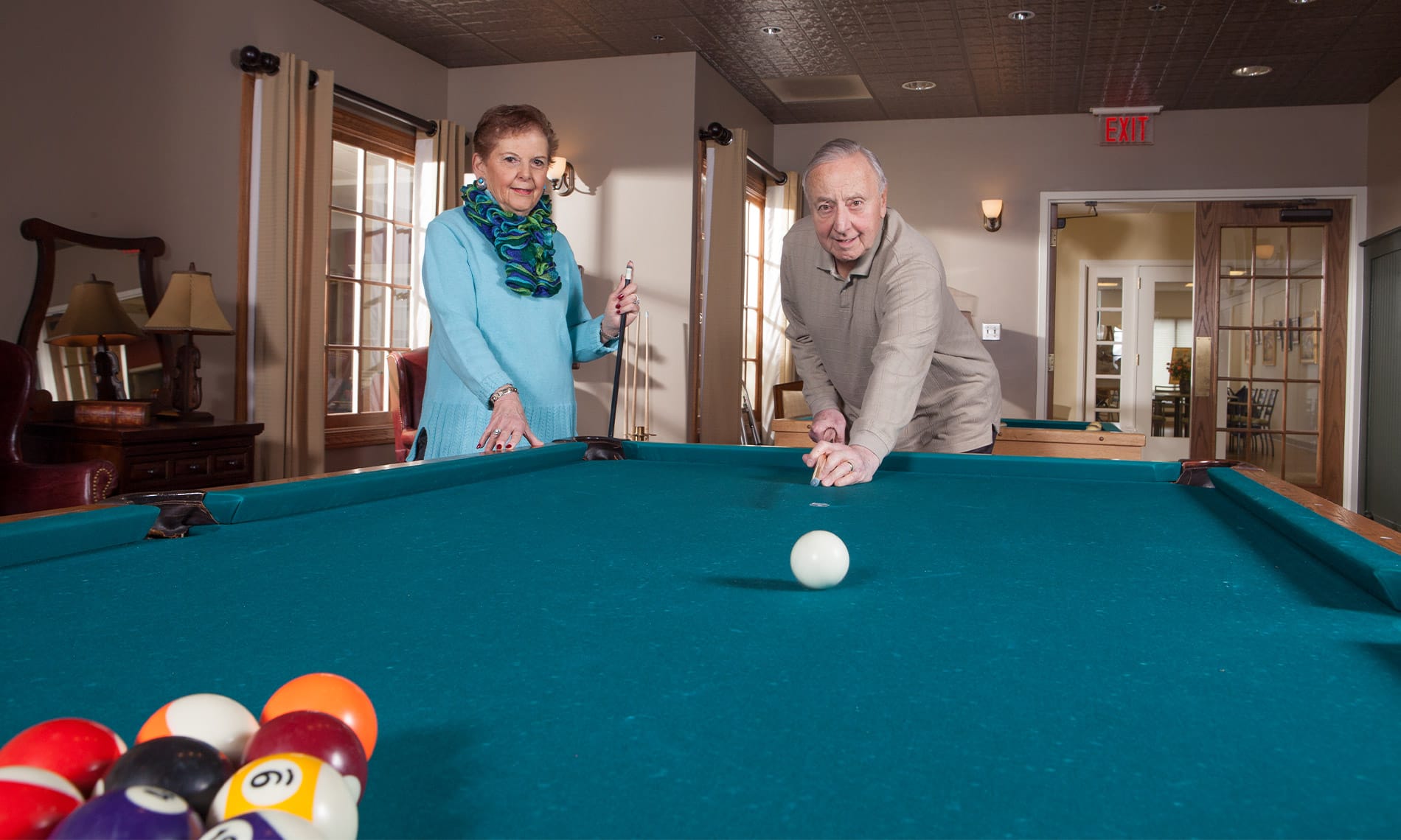 An elderly couple playing billiards