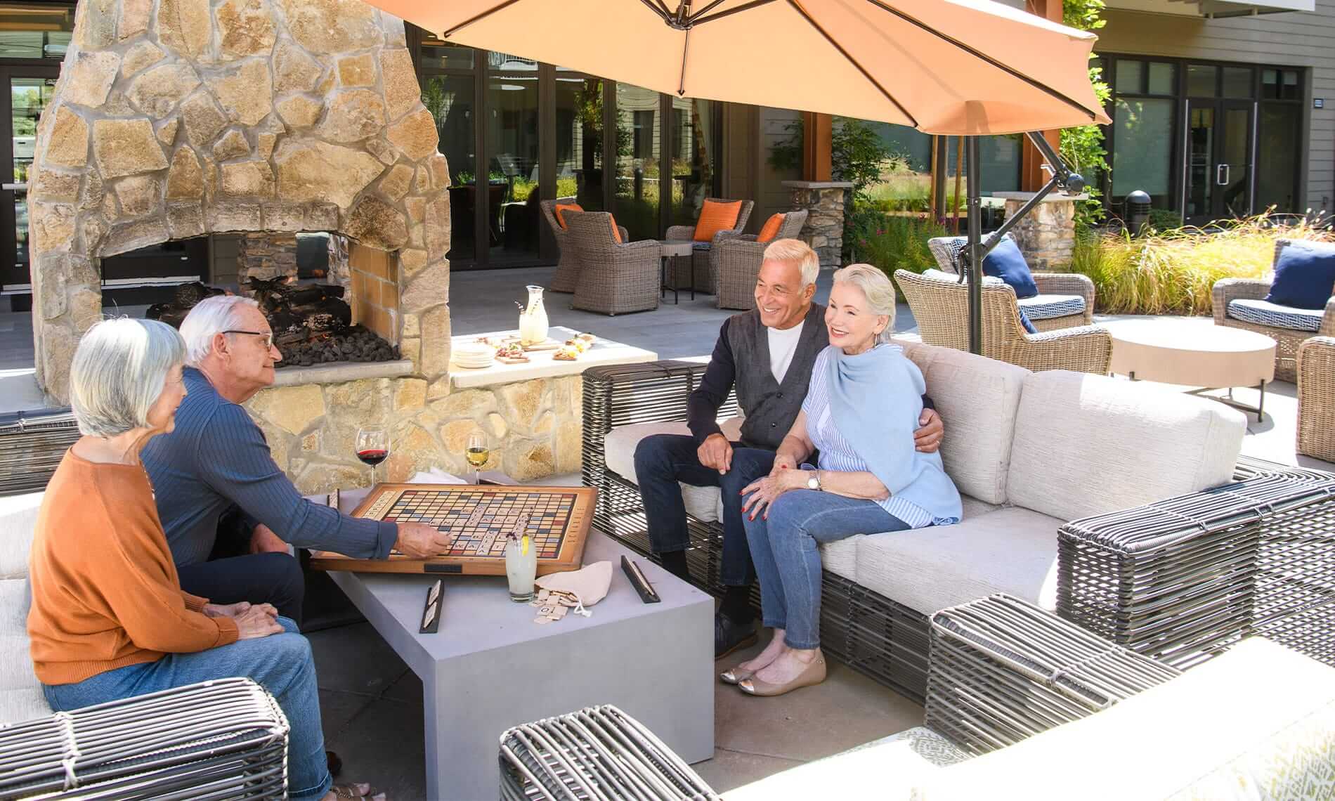 A group of seniors enjoy a game of scrabble outdoors while enjoying alcoholic and non-alcoholic beverages