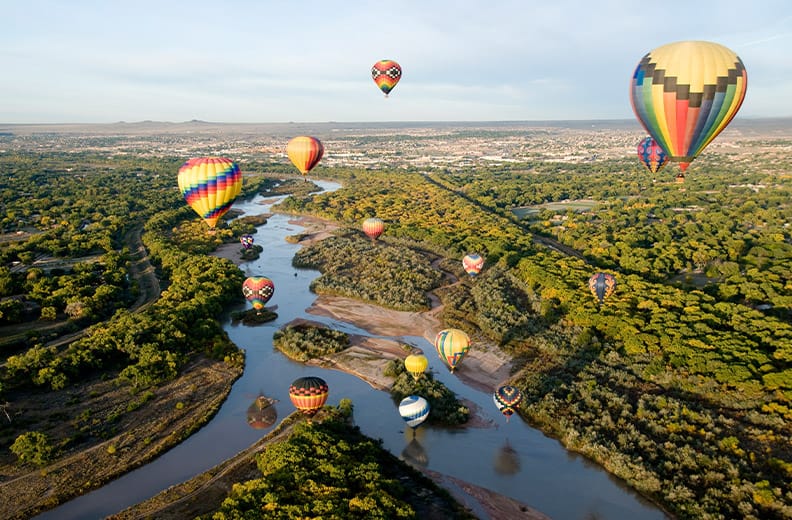Hot air balloons drifting over the Rio Grande river in Albuquerque, New Mexico.