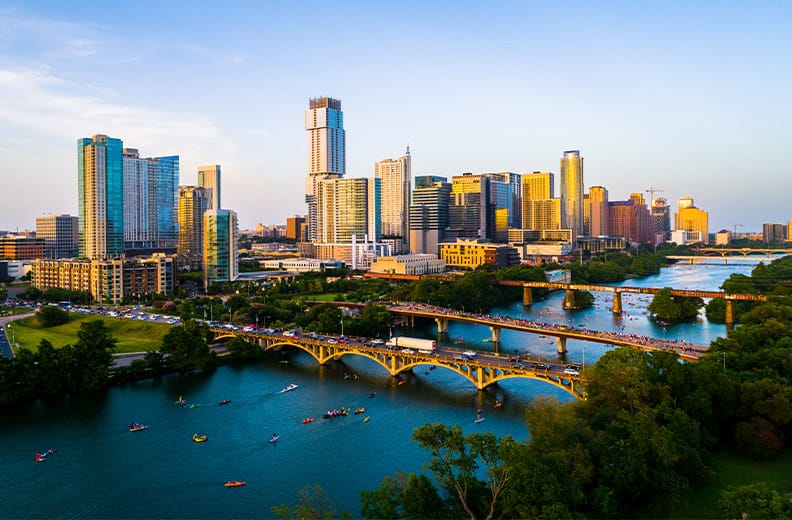 Awei drone views at golden hour Austin Texas sunset of a modern future city above green landscape cityscape above Town lake or Lady Bird Lake bridges and towers packing with kayakers.