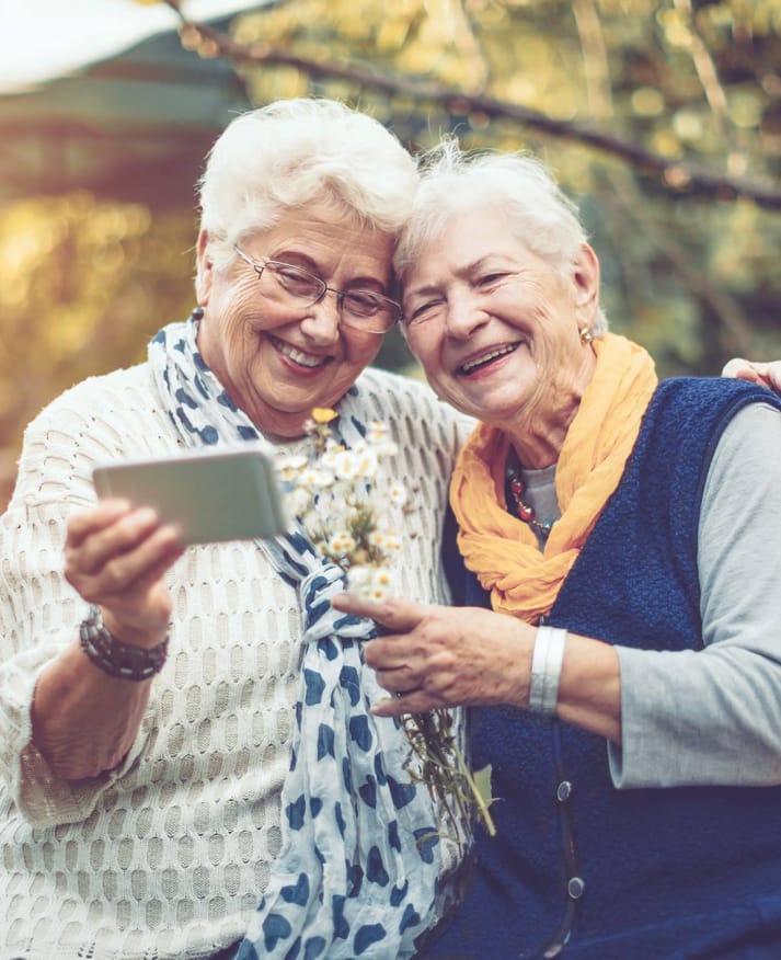 elderly woman laughing and looking at a mobile device