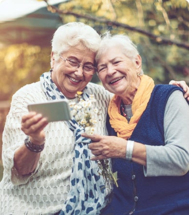 elderly woman laughing and looking at a mobile device