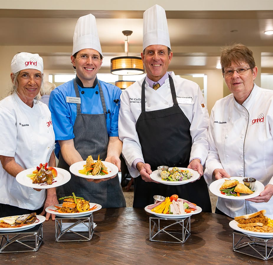 Nourish Watermark Community chefs displaying a variety of meals they have prepared on-site for residents
