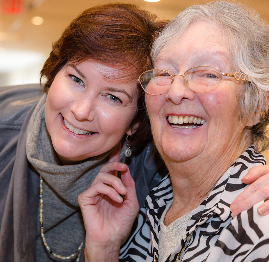An elderly woman and her daughter laughing An elderly woman and her daughter laughing