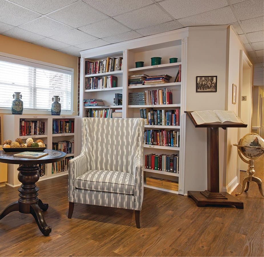 The Fountains at the Albemarle Library A chair and table in front of a built in book shelf within the on-site library at the Fountains at the Albemarle