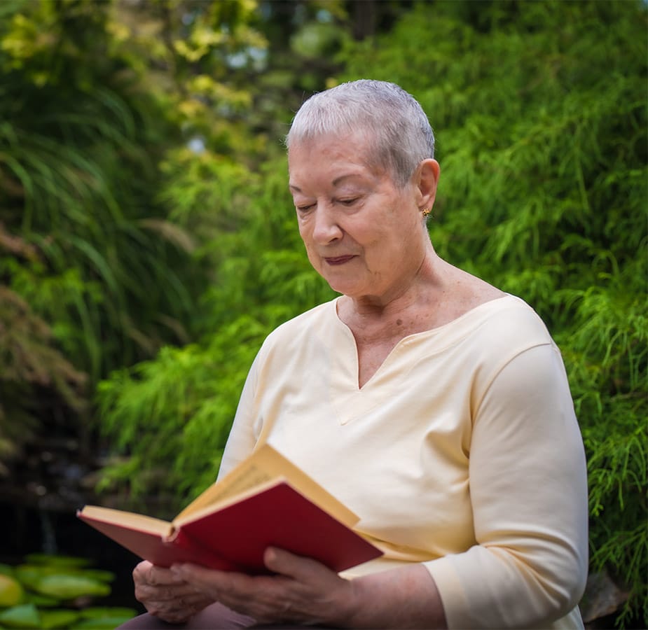 Mind An elderly woman reads a book surrounded by lush greenery