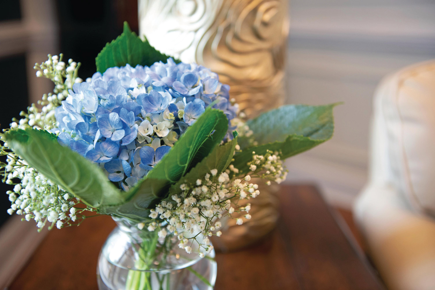 The Fountains at Albemarle A glass vase with a blue and white floral arrangement set atop a wooden table