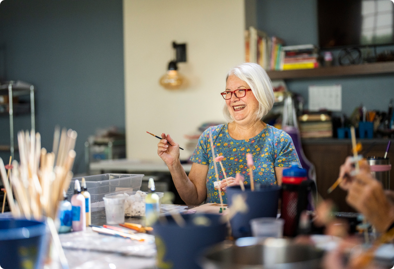 elderly woman laughing while holding a paintbrush elderly woman laughing while holding a paintbrush