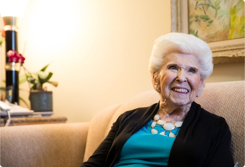 elderly woman sitting on a couch laughing elderly woman sitting on a couch laughing