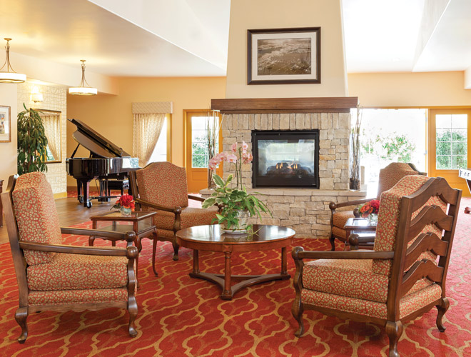 3d tour Hall with armchair, fireplace and a grand piano in the back by the bright windows