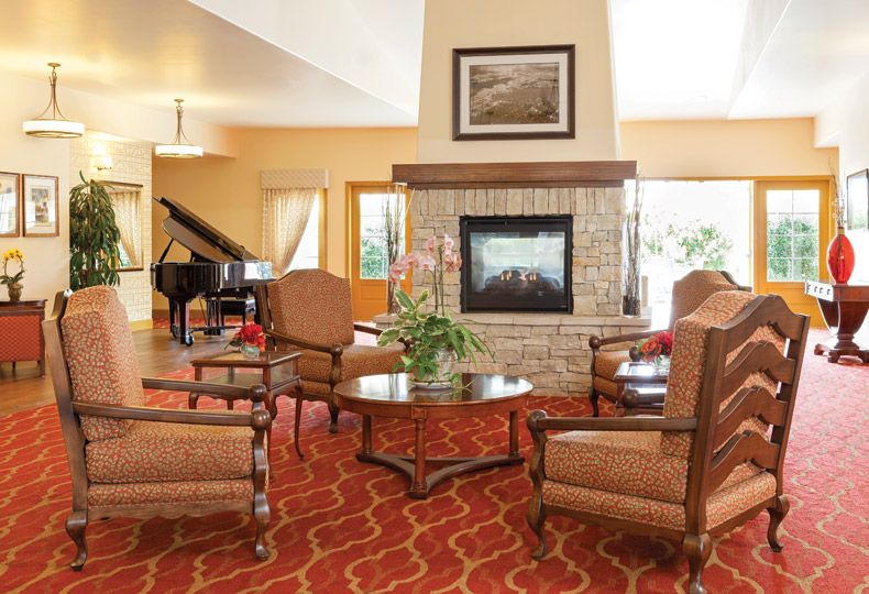 3d tour Hall with armchair, fireplace and a grand piano in the back by the bright windows