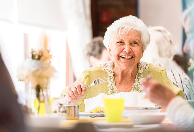 Memory a lady resident having dinner and laughing with her peers