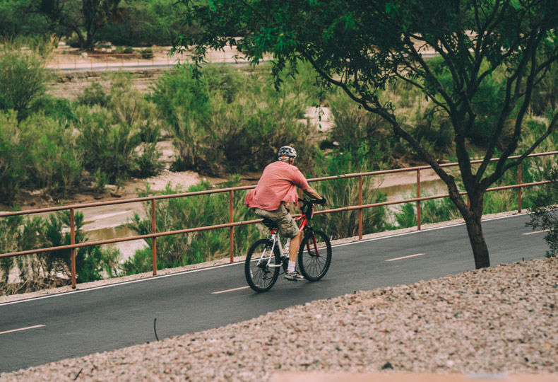 The Hacienda at the Rivers A resident enjoying an outdoor bike ride on a pathway in Tucson, AZ