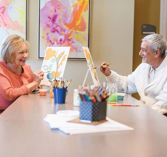 The Preston at the Park Cities A man and a woman sitting at a table painting with water colours